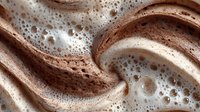 Swirled chocolate and vanilla cream with bubbles creating marbled pattern for dessert backgrounds and culinary designs.