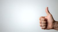 Hand showing thumbs up gesture on clean white background for positive feedback and approval concepts in business presentations.