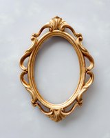 Ornate vintage gold baroque frame with oval shape and decorative carved floral elements on light gray wall, empty mirror or photo frame for elegant interior design.