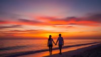 Romantic couple holding hands walking on beach at sunset with dramatic orange and pink sky reflecting on ocean waves creating peaceful evening atmosphere.