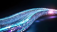 Glowing blue and purple light trails with sparkling particles flowing in curved motion against dark background, creating dynamic energy effect.