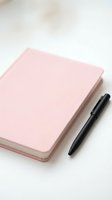 Closed pink notebook with black pen on white surface, ready for writing, planning, journaling, and creative projects.