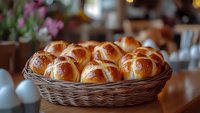Fresh homemade bread rolls with glossy golden crust arranged in woven basket on wooden table, soft natural lighting creates warm ambiance for food photography.