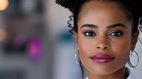 Young African American woman with natural curly hair and silver hoop earrings smiling confidently against blurred background. Professional makeup and glowing skin showcase modern beauty.