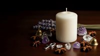 Spa wellness setup with cream candle, amethyst crystals, lavender, star anise spices on wooden surface for relaxation and aromatherapy meditation.
