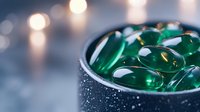Green gel capsules in a dark bowl with water droplets, soft bokeh lights in background, wellness and supplement concept for healthcare, nutrition, and pharmaceutical industry use.