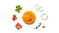 Fresh ingredients arranged on white background with spiral orange puree, diced vegetables, herbs and onion rings for culinary preparation and cooking.