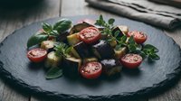 Fresh Mediterranean salad with cherry tomatoes, olives and herbs on dark slate plate for healthy dining and culinary presentations.
