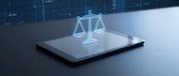 Glowing holographic scales of justice projected above a digital tablet on a dark surface, symbolizing legal technology and online law concepts.