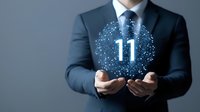 Businessman in dark suit holding glowing digital number 11 surrounded by network connections, representing technology innovation and business analytics.