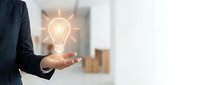 Businessman holding glowing light bulb in hand representing innovation, creativity, and bright ideas for business success and entrepreneurship.