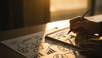 Business professional drawing strategic planning diagrams and charts on paper with pen in warm office lighting for corporate development presentations.