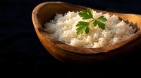 Cooked white rice with fresh parsley garnish served in rustic wooden bowl on dark background for culinary presentations and food styling projects.