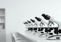Row of professional laboratory microscopes on white table in modern research facility for scientific analysis and medical diagnostics.