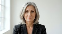 Mature woman with gray hair wearing dark blazer, professional headshot for corporate business portraits and executive profiles.