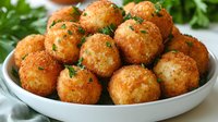 Golden crispy potato croquettes garnished with fresh parsley served on white ceramic plate, close up view of homemade appetizer with creamy filling.