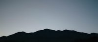 Mountain silhouette against clear sky at dawn or dusk, suitable for backgrounds, nature themes, and landscape design projects.