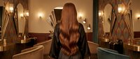 Young woman with long brown hair in elegant bathroom with golden fixtures and warm lighting for luxury spa and wellness concepts.