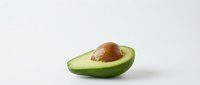 Fresh ripe avocado half with brown pit on clean white background isolated for healthy food design and culinary projects.