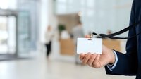 Professional holding blank ID badge with lanyard in office environment, suitable for corporate identity, security, employee recognition, and business communications.