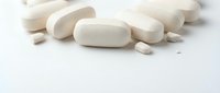 White pharmaceutical pills and capsules scattered on clean surface for medical and healthcare concepts.