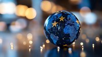 Glass globe with world map silhouette and decorative golden stars against blurred bokeh lights background creates magical holiday atmosphere.