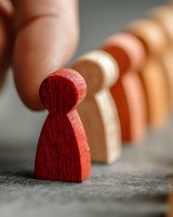 Red wooden figure standing out from row of neutral-colored figures, symbolizing leadership, individuality, and team management concepts.
