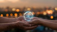 Hands holding glowing Earth globe with bokeh city lights at sunset symbolizing environmental protection, sustainability and global responsibility.