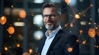 Confident mature businessman with gray beard and glasses smiling against digital network visualization with glowing orange bokeh lights in corporate office.