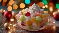 Festive holiday fruit salad with whipped cream in glass bowl surrounded by colorful Christmas lights and ornaments creating warm celebratory atmosphere.