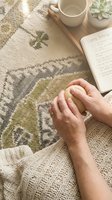 Mature woman hands holding a smooth stress ball beside a coping techniques journal, cozy rug and tea cup, mental wellness concept.