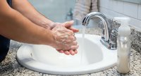 Man washing hands with soap at bathroom sink with running water for hygiene and cleanliness routine.