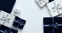 Luxury gift boxes with silver and navy blue ribbons arranged on white background, overhead flat lay composition for holiday shopping, celebrations, and special occasions.