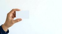 Hand holding blank white business card isolated on light background, ready for branding and corporate design mockups.