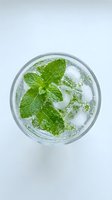 Refreshing mint cocktail with ice cubes in glass viewed from above on white background for beverage and drink concepts.