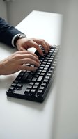 Professional businessman hands typing on black computer keyboard at modern office desk for business communication and productivity work.