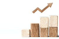 Wooden blocks arranged as ascending bar chart with upward trending arrow, symbolizing business growth and financial success.