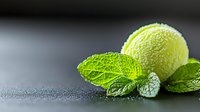 Fresh tennis ball shaped lime ice cream scoop with bright green mint leaves on dark background with water drops, macro food photography for dessert menu.