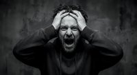 Stressed middle-aged Caucasian man screaming with hands on head expressing mental breakdown, anxiety and emotional pain in dramatic black and white portrait.