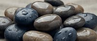 Smooth river stones with water droplets in natural earth tones creating zen spa atmosphere for meditation and wellness concepts.