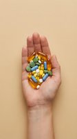 Open palm holding assorted colorful vitamin capsules and pills in yellow, blue, green and white on neutral background for healthcare, wellness and supplement concepts.