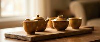 Traditional ceramic tea set with covered bowls arranged on wooden serving board in warm natural lighting for authentic tea ceremony experience.