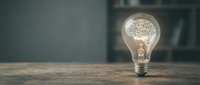 Light bulb with brain inside representing creativity, innovation and bright ideas on wooden desk with blurred background for business concepts.