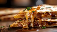 Grilled quesadilla with melted cheese dripping down layers of tortillas filled with sausage and herbs on wooden surface, close up view with selective focus.