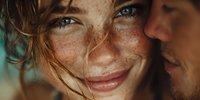 Close-up portrait of smiling young Caucasian woman with freckles and green eyes next to male partner in warm natural lighting for lifestyle photography.