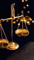 Golden scales of justice with law book against warm bokeh lights background symbolizing legal system fairness and judicial balance.