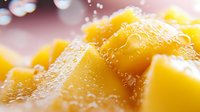 Fresh juicy mango chunks in extreme macro view showing detailed fruit texture with water droplets and natural light bokeh effect in background.