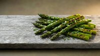 Fresh green asparagus spears seasoned with herbs and spices on rustic wooden cutting board, healthy organic vegetable ingredient for cooking and nutrition.