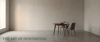 Minimalist interior space featuring a small wooden desk with laptop and chair against neutral beige walls, representing downsizing and minimalist living for home design projects.