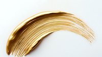 Golden metallic curved brush stroke on white background, luxury cosmetic smear texture isolated for creative design and makeup artistry applications.